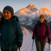Two women trekking through snowy Himalayan trails at sunrise with Mount Everest glowing in the background, representing female-guided empowerment trekking in Nepal.