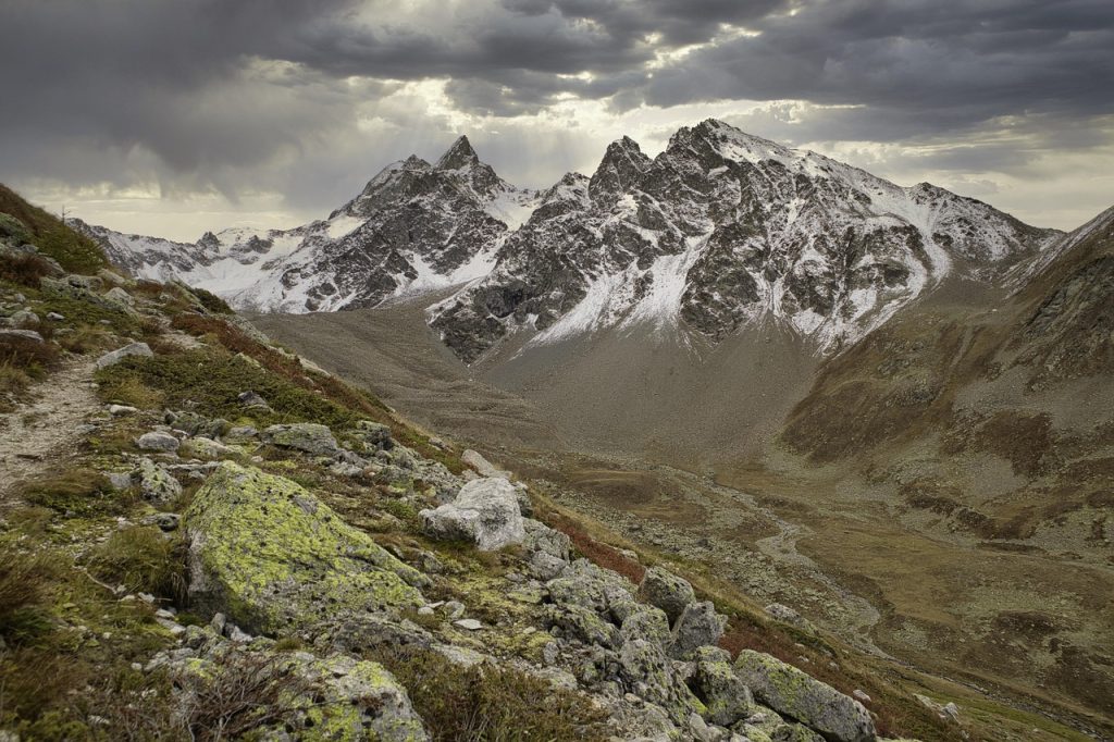 Snow-covered alpine peaks under clear blue skies with rugged terrain in the foreground.